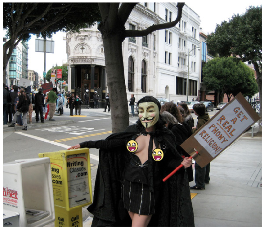 «Raidfag Wench» de Anonymous manifestándose contra la Iglesia de la Cienciología, 2008. (en el cartel: «Conseguid una verdadera religión falsa») 